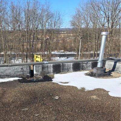 A flat roof with patches of snow and visible wear, showing the impact of winter weather on roofing materials.
