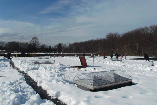 deep snow on a commercial flat roof with a crew working on snow removal.